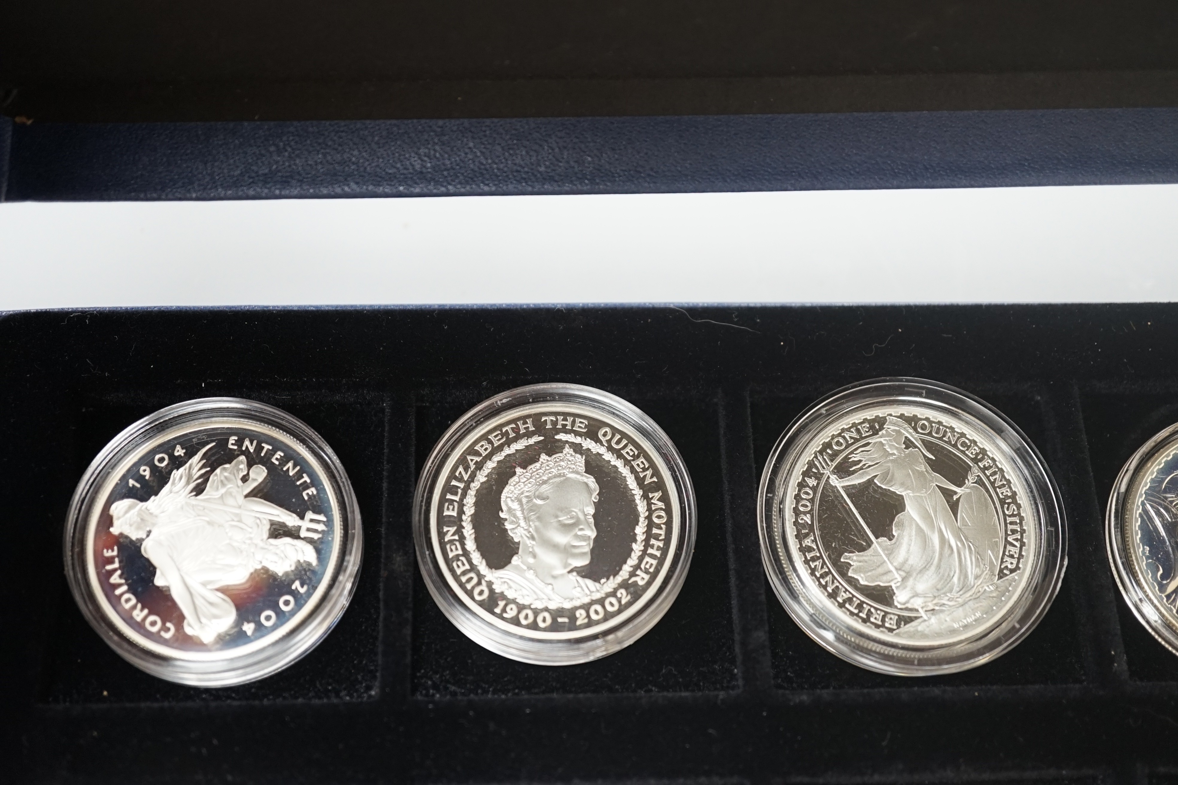 A group of coins including 1898 British Trade One Dollar, Royal Mint UK two QEII five shillings, 1935 crown, 1890 crown, silver proof coins - five 1oz. silver Britannia £2 coins 1998-2000, 2003, 2004, 2002 Queen Mother £